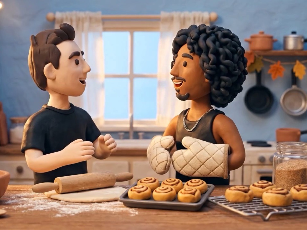 two clay bakers in a home kitchen, one holding a tray of fresh rolls