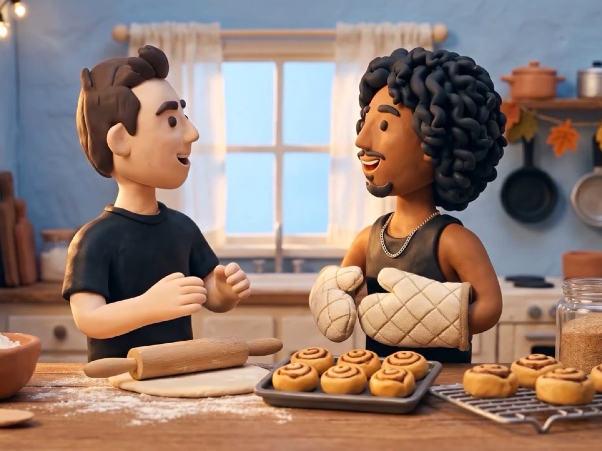 two clay bakers in a home kitchen, one holding up a tray of fresh rolls